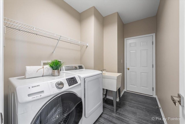 clothes washing area with dark wood finished floors, laundry area, baseboards, and washing machine and clothes dryer