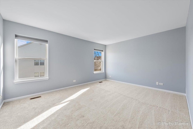 spare room with carpet flooring, visible vents, and baseboards