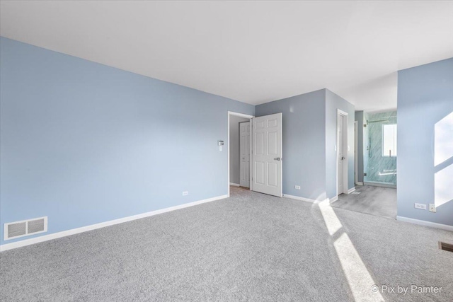 unfurnished bedroom featuring carpet, ensuite bath, baseboards, and visible vents