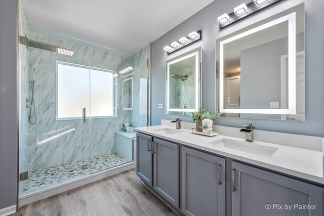 bathroom with wood finished floors, a marble finish shower, and a sink