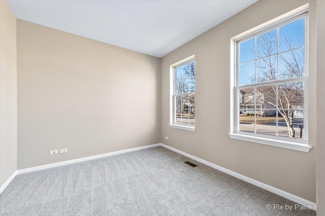 carpeted spare room featuring visible vents and baseboards