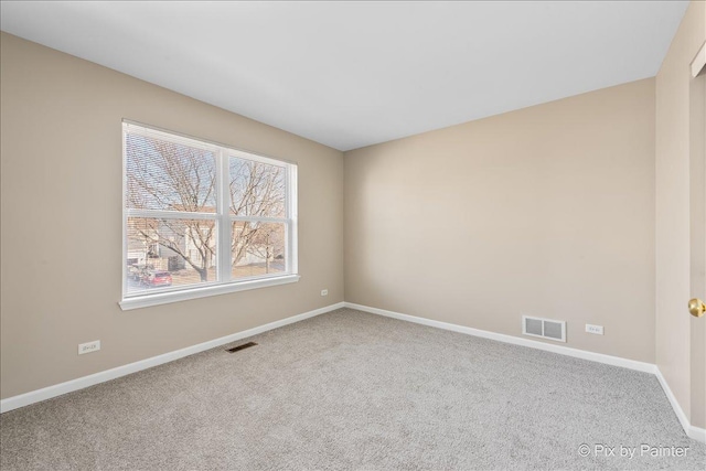 carpeted spare room featuring baseboards and visible vents