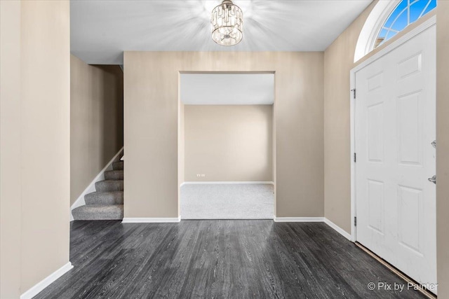 entrance foyer with a chandelier, stairway, baseboards, and wood finished floors