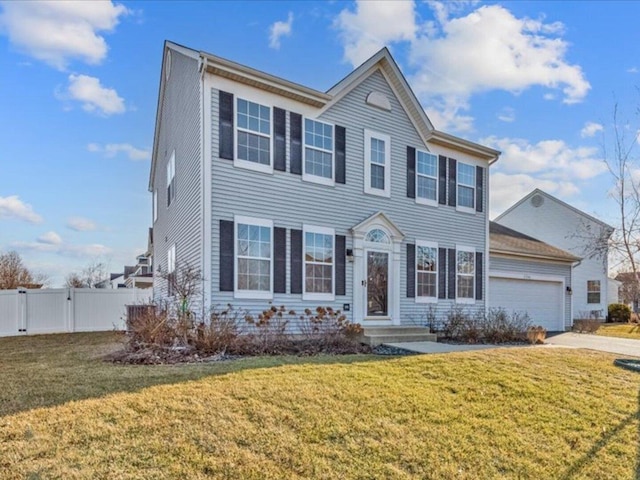 colonial home featuring a gate, fence, a front lawn, concrete driveway, and a garage