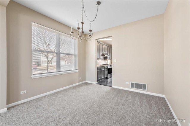 spare room with baseboards, visible vents, dark colored carpet, and a chandelier