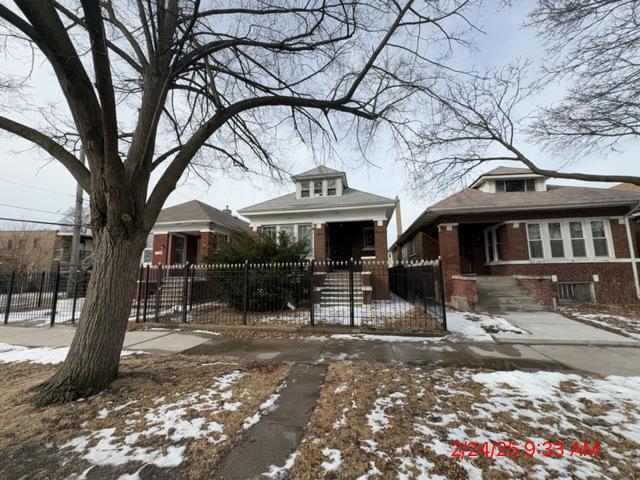 bungalow with a fenced front yard and brick siding