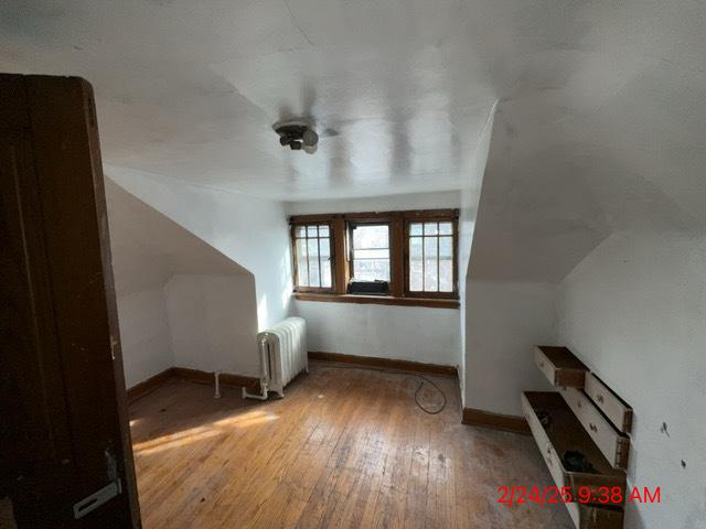 additional living space featuring baseboards, radiator heating unit, and hardwood / wood-style flooring