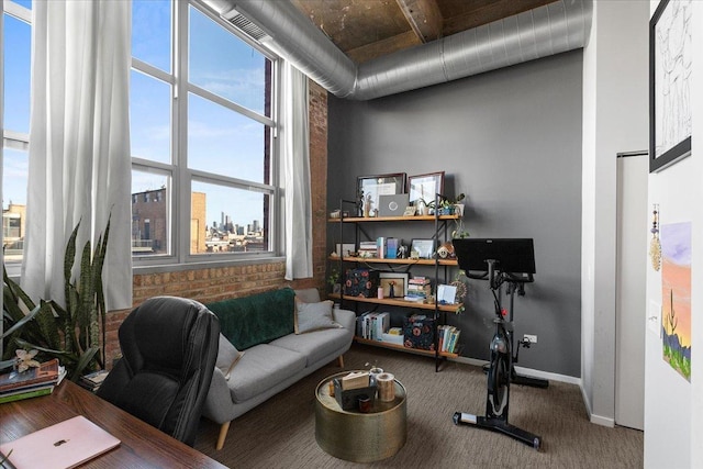 office area with carpet flooring, brick wall, a high ceiling, and baseboards