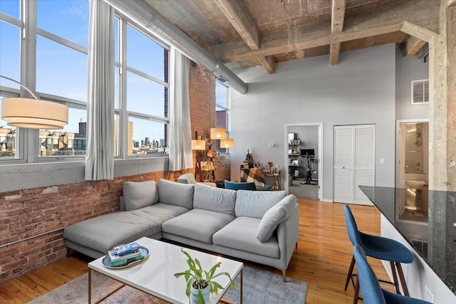 living room featuring visible vents, beam ceiling, a high ceiling, and wood finished floors