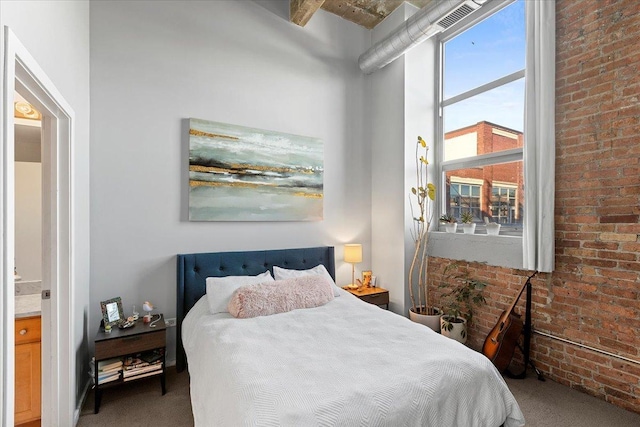 carpeted bedroom with visible vents and brick wall