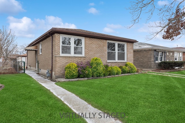 view of front of home featuring a front yard, fence, and brick siding