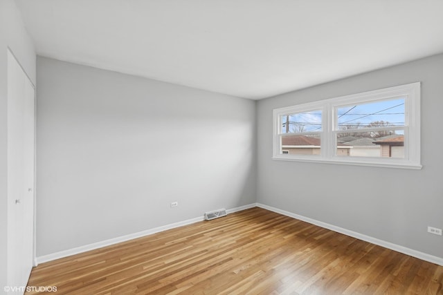 empty room featuring visible vents, light wood-type flooring, and baseboards