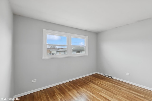 empty room with light wood-type flooring, visible vents, and baseboards