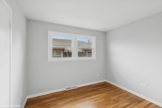 spare room with visible vents, baseboards, and wood finished floors