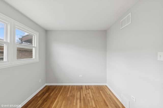 unfurnished room with visible vents, baseboards, and wood finished floors