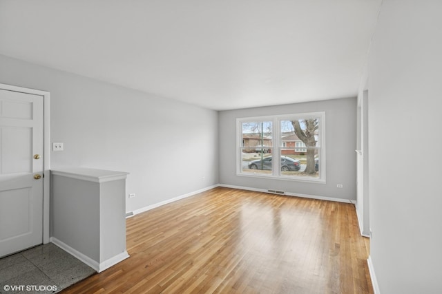 spare room featuring light wood-style flooring, baseboards, and visible vents