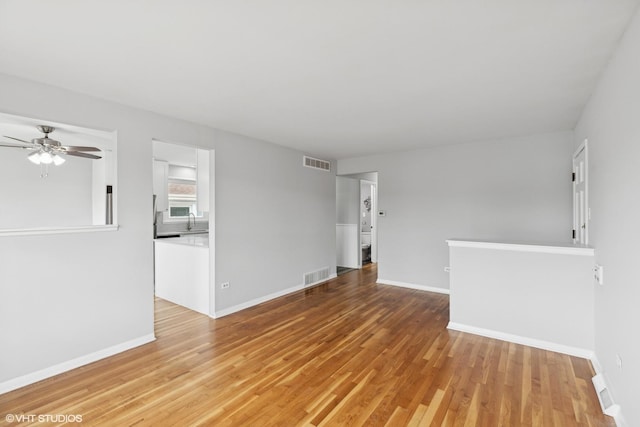 spare room featuring a sink, visible vents, baseboards, and light wood finished floors