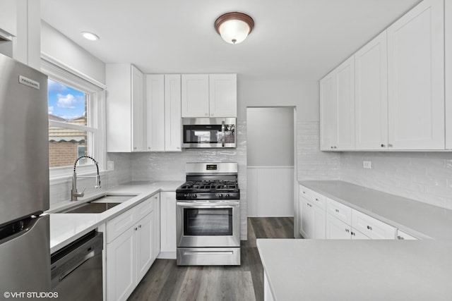 kitchen with dark wood finished floors, white cabinetry, stainless steel appliances, and a sink