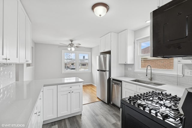 kitchen with light countertops, white cabinets, appliances with stainless steel finishes, and a sink