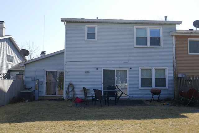 back of property with central air condition unit, a lawn, and fence