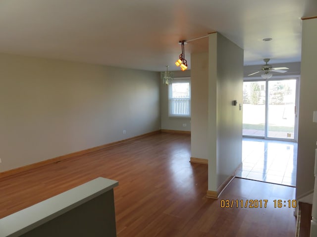 empty room featuring ceiling fan, baseboards, and wood finished floors