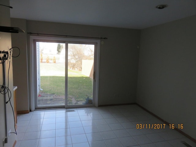 empty room featuring light tile patterned floors, visible vents, and baseboards