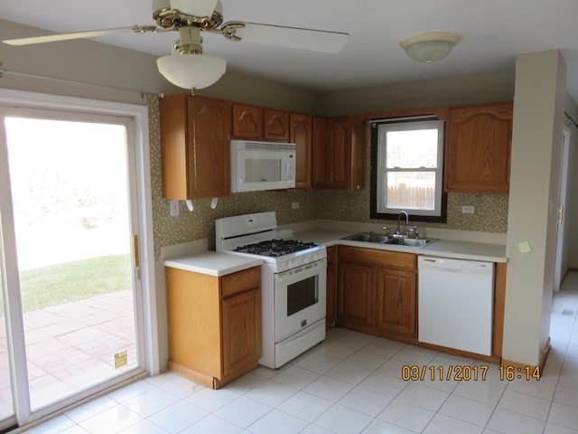 kitchen with a ceiling fan, a sink, tasteful backsplash, white appliances, and light countertops