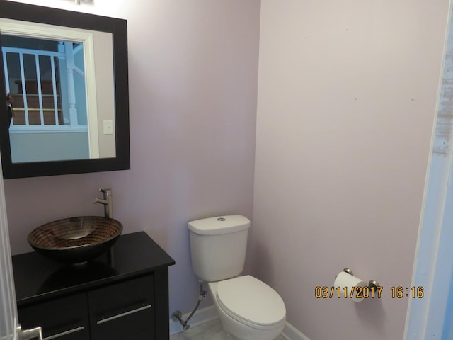 bathroom with toilet, vanity, and baseboards