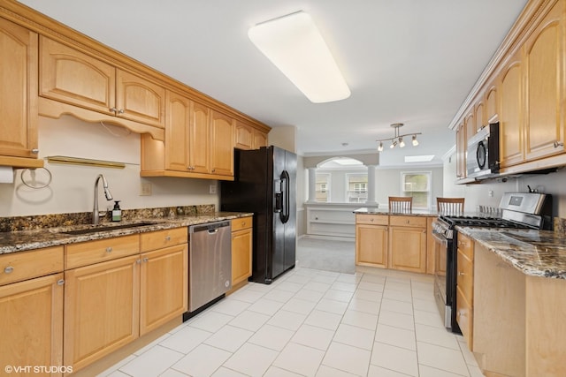 kitchen with appliances with stainless steel finishes, a sink, arched walkways, a peninsula, and light carpet