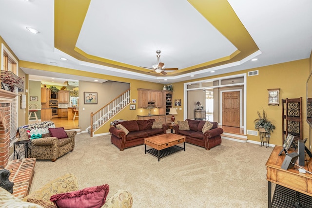 living room with visible vents, a fireplace, stairway, and a raised ceiling