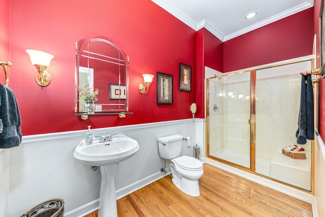 full bathroom featuring wood finished floors, a wainscoted wall, a shower stall, crown molding, and toilet