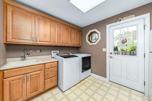 clothes washing area with a sink, cabinet space, light floors, and washer and clothes dryer