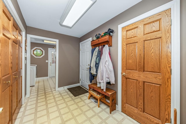 mudroom featuring washer / dryer, light floors, and baseboards