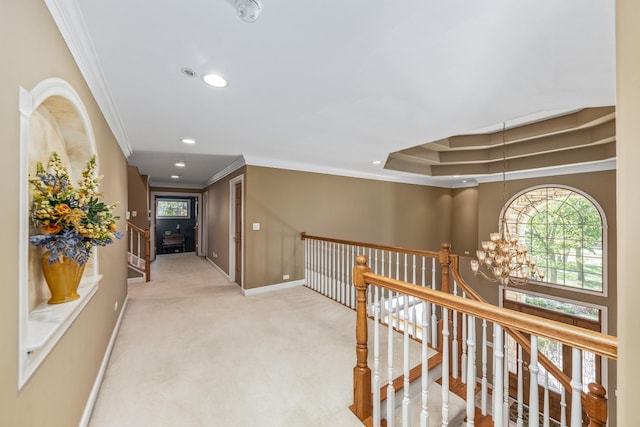 hallway with baseboards, ornamental molding, a wealth of natural light, carpet floors, and an inviting chandelier