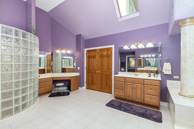 bathroom with vanity, decorative columns, a tub to relax in, and high vaulted ceiling