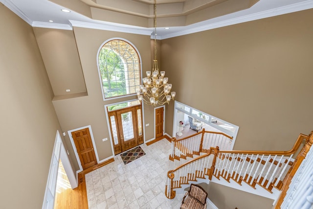 entryway with baseboards, stairs, ornamental molding, a high ceiling, and an inviting chandelier