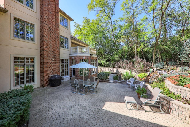 view of patio featuring a balcony, outdoor dining area, and grilling area