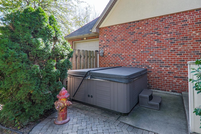 view of patio / terrace featuring a garage and a hot tub