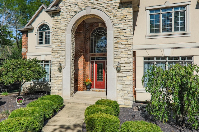 doorway to property with stone siding and stucco siding