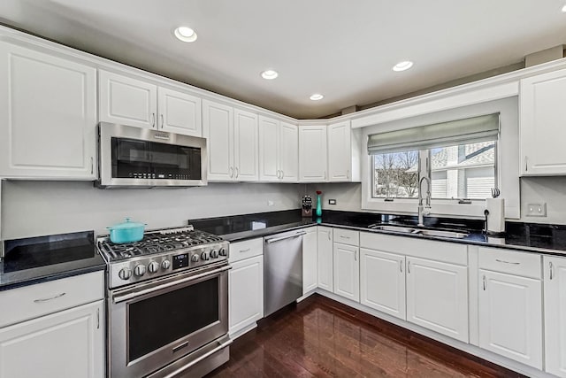 kitchen with dark countertops, dark wood-style flooring, appliances with stainless steel finishes, and a sink