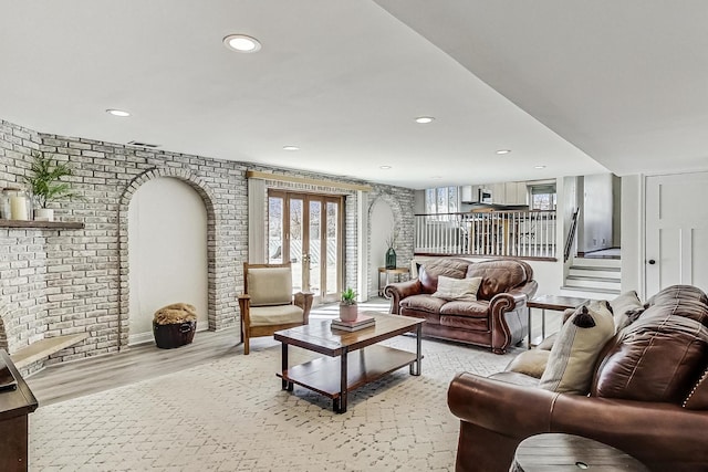 living area with brick wall, plenty of natural light, and light wood finished floors