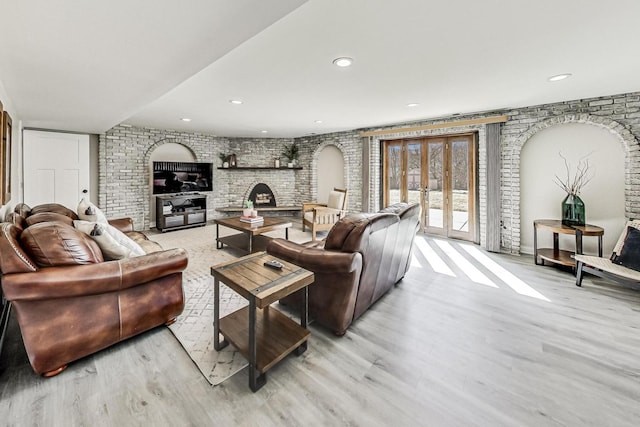 living room with recessed lighting, french doors, brick wall, a fireplace, and light wood finished floors