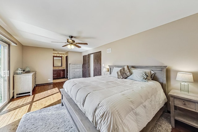 bedroom featuring ceiling fan, visible vents, ensuite bath, and wood finished floors