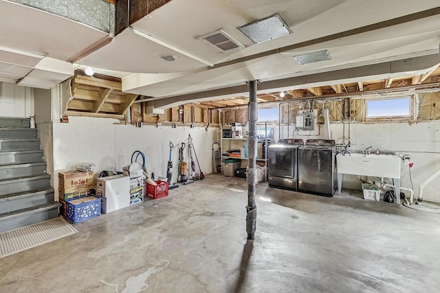 below grade area with visible vents, washer and clothes dryer, a sink, electric panel, and stairway