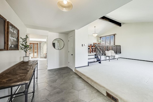 interior space featuring dark colored carpet, visible vents, plenty of natural light, and lofted ceiling with beams