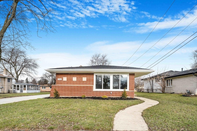 view of front of property with a front yard, cooling unit, and brick siding