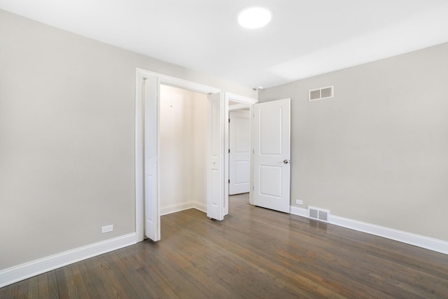 unfurnished bedroom with visible vents, baseboards, and dark wood finished floors