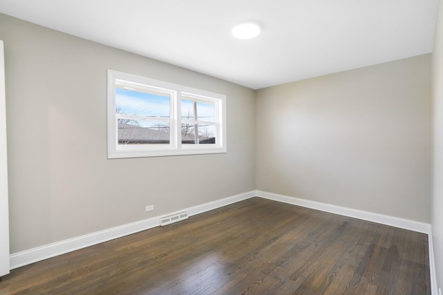 empty room with visible vents, baseboards, and dark wood-style floors