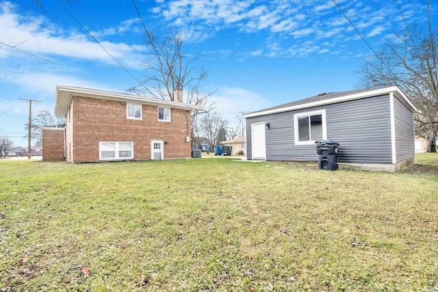 back of house featuring a lawn, brick siding, and a chimney