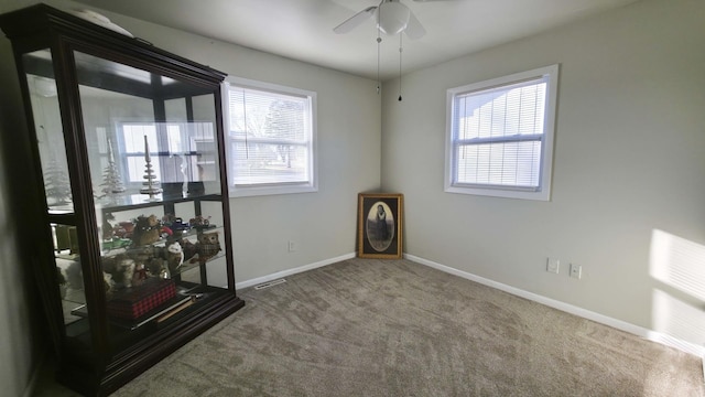 carpeted empty room with visible vents, baseboards, and ceiling fan